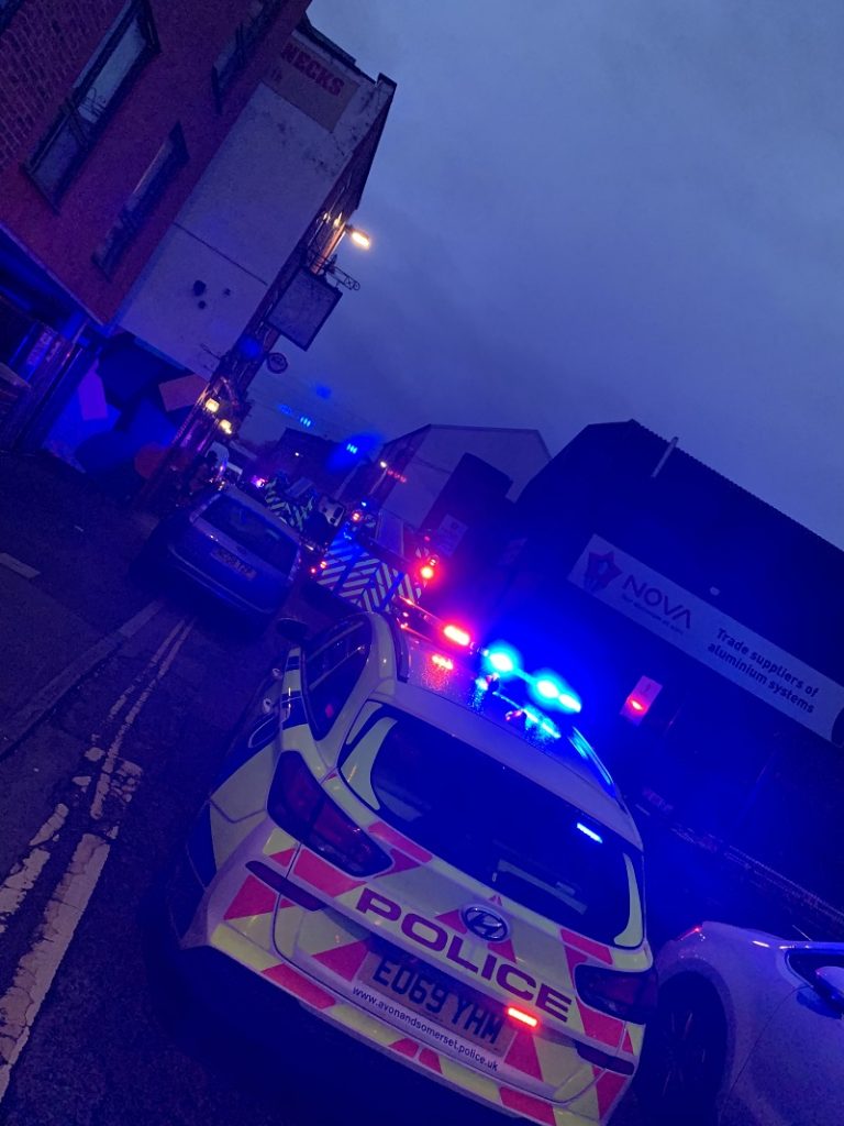 Bristol fire St Jude's - photo is hazy with lots of blue lights. In the foreground is the back of a police car with fire engines in the distance