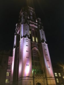 Bristol University Tower Tours. A photo of the Wills Memorial Tower at night lit up in purple lighting